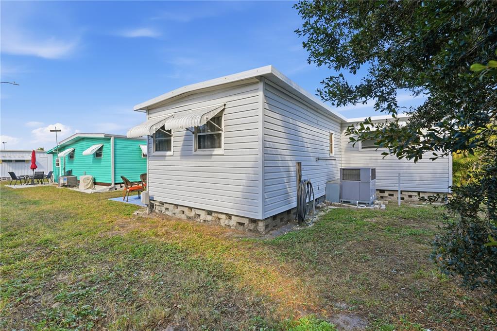 The exterior of a light gray mobile home with a metal awning and concrete block foundation — 82008 A STREET N UNIT 8, PINELLAS PARK, FL