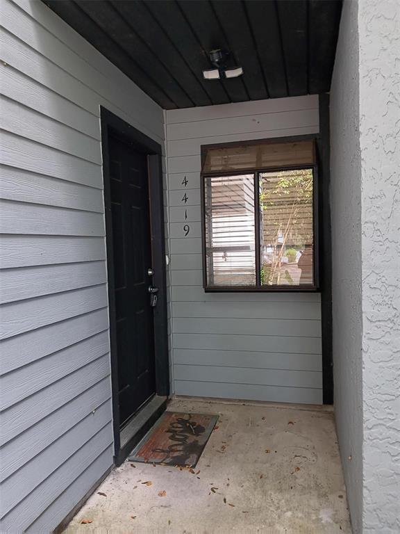 A front entryway with a black door, a window, and light gray horizontal siding — 4419 SW 20TH LANE, GAINESVILLE, FL