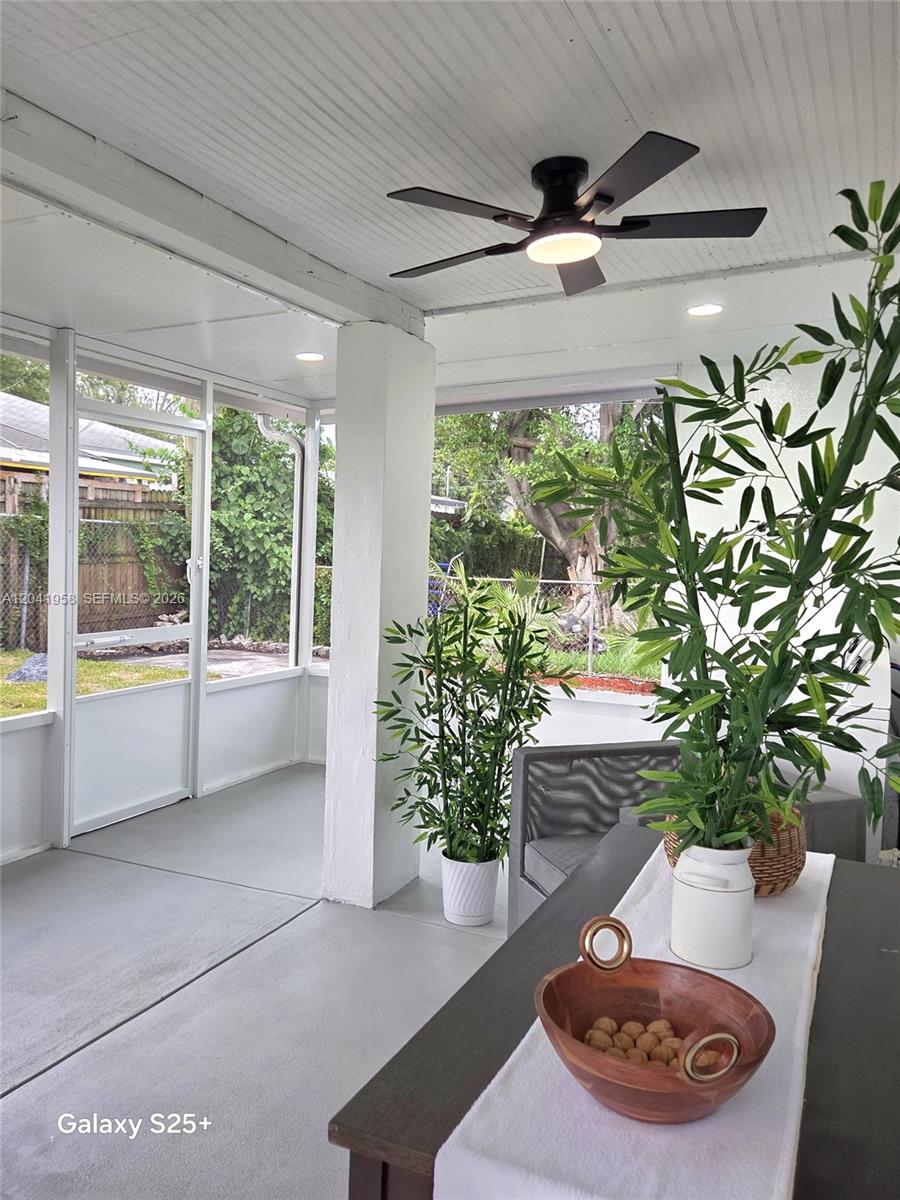 A screened-in porch features a ceiling fan, gray flooring, and a dining table with plants — 1321 NW 82nd St, Miami FL 33147, MIAMI, FL
