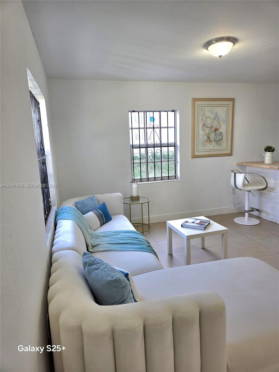 A living room features a white sectional sofa, a small coffee table, and a bar stool — 1321 NW 82nd St, Miami FL 33147, MIAMI, FL