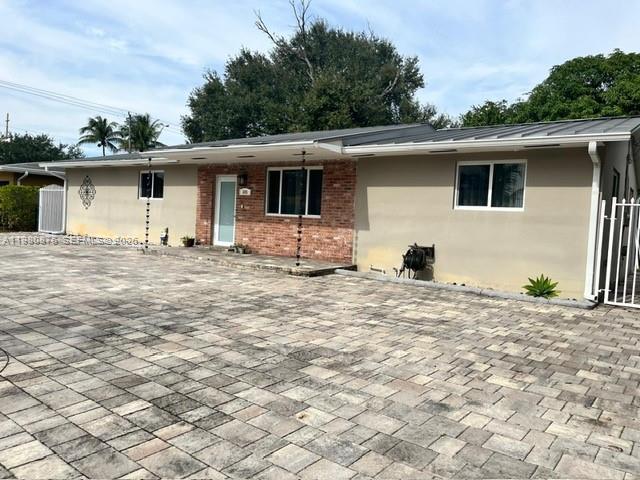 A single-story house with a brick facade, beige siding, and a large paved driveway — 685 W 77th St, Hialeah FL 33014, HIALEAH, FL