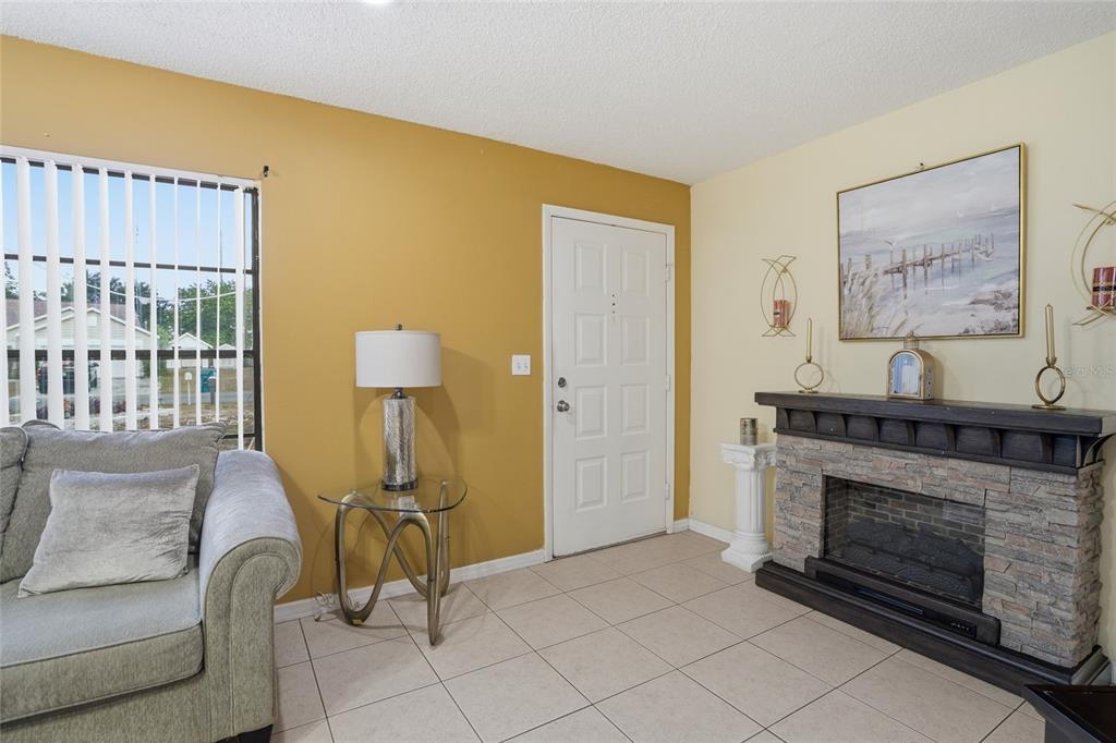 A living room features a stone fireplace, a white front door, and tile flooring — 10164 GIFFORD DRIVE, SPRING HILL, FL