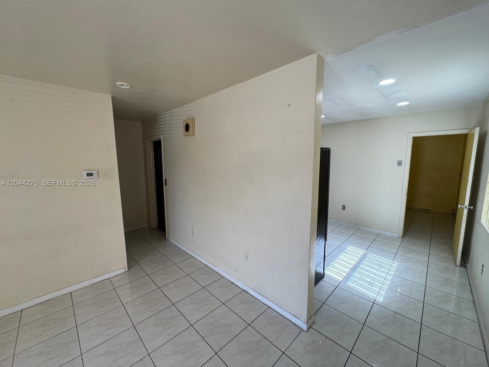 An interior view shows a tiled room with a partial wall and open doorways — 2428 NW 82nd St # 2428, Miami FL 33147, MIAMI, FL