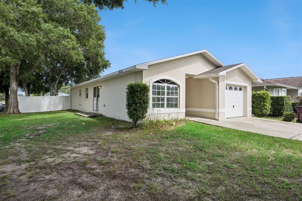 A single-story house with a white stucco exterior, a garage, and a large side yard — 1601 WYOMING AVENUE, ST CLOUD, FL