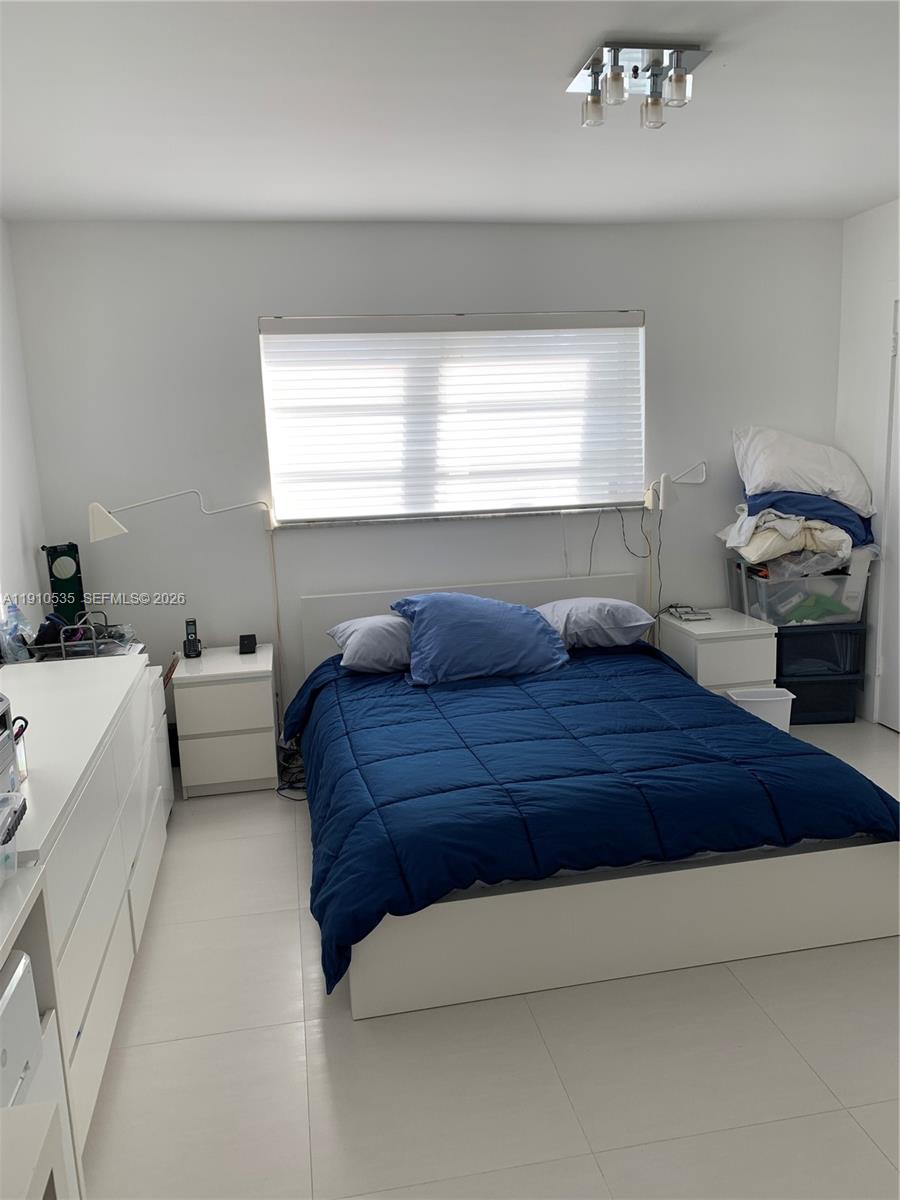 A bedroom features a blue comforter, white furniture, and a window with blinds — 1501 Arthur St # 10, Hollywood FL 33020, HOLLYWOOD, FL