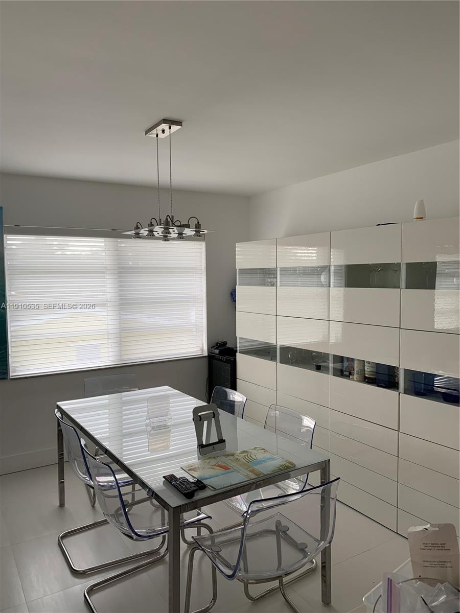 A dining room features a glass-topped table, clear chairs, and a large white storage unit — 1501 Arthur St # 10, Hollywood FL 33020, HOLLYWOOD, FL