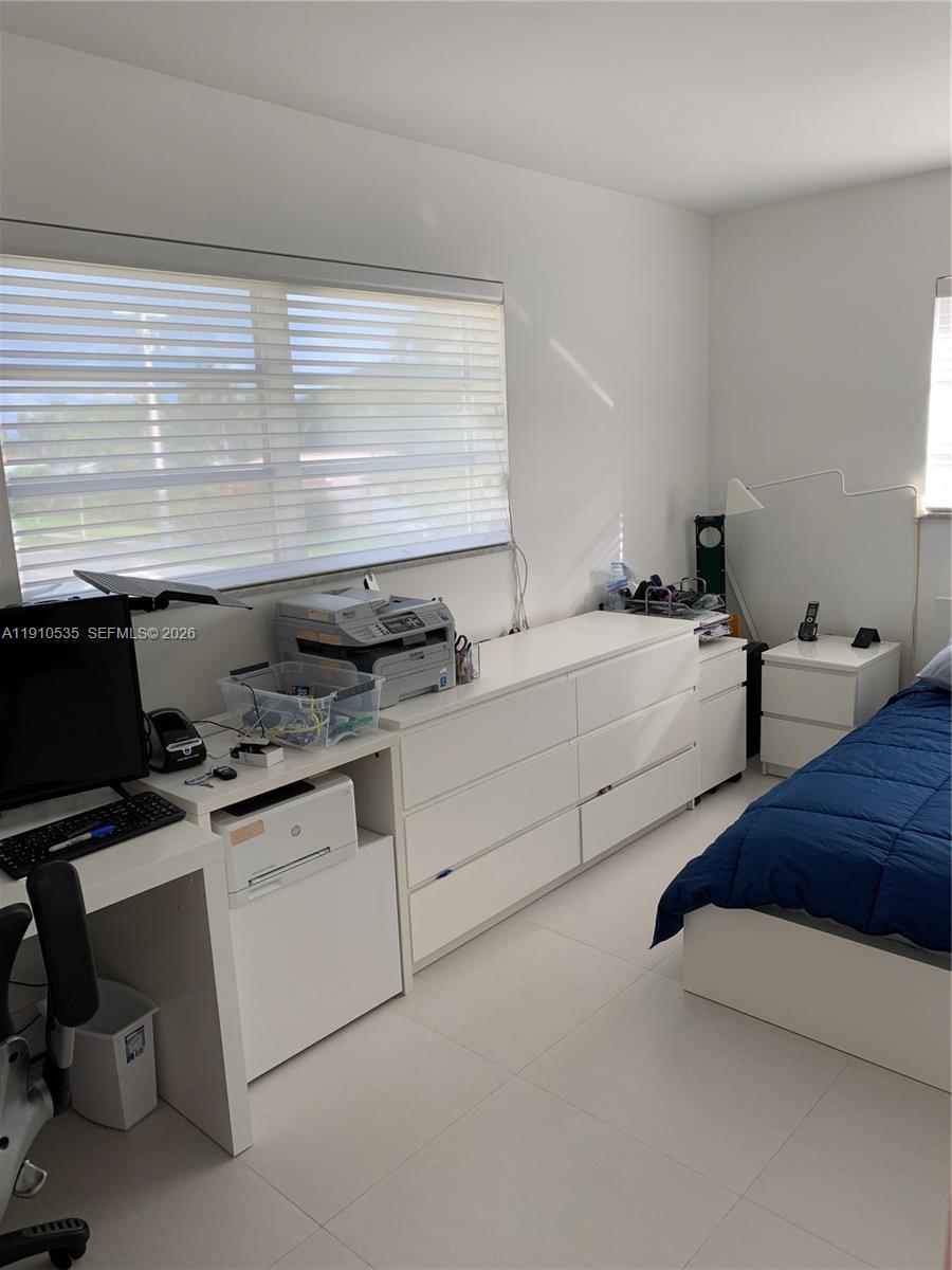 A bedroom features white furniture, a desk with a computer, and a blue bedspread — 1501 Arthur St # 10, Hollywood FL 33020, HOLLYWOOD, FL