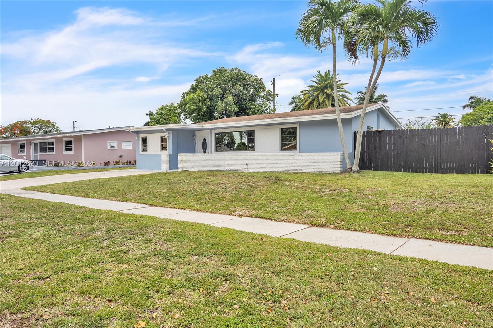 A single-story blue house with a white brick wall and palm trees in the yard — 6133 NW 20th St, Margate FL 33063, MARGATE, FL