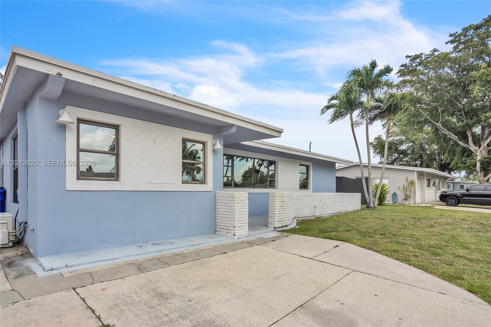 A light blue single-story house features white brick accents and a concrete driveway — 6133 NW 20th St, Margate FL 33063, MARGATE, FL