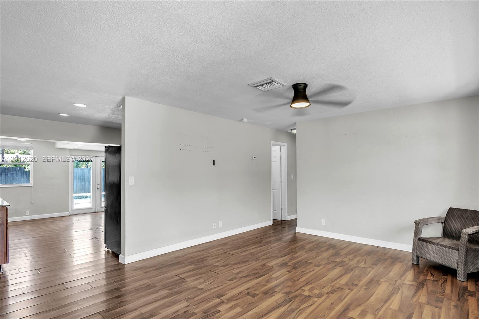 A living room with wood-look flooring, a ceiling fan, and a single wicker chair — 6133 NW 20th St, Margate FL 33063, MARGATE, FL