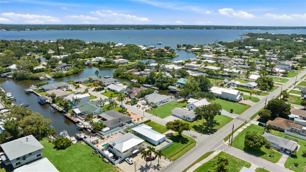 An aerial view shows a residential neighborhood with houses along a canal and a bay — 912 21ST AVENUE W, PALMETTO, FL