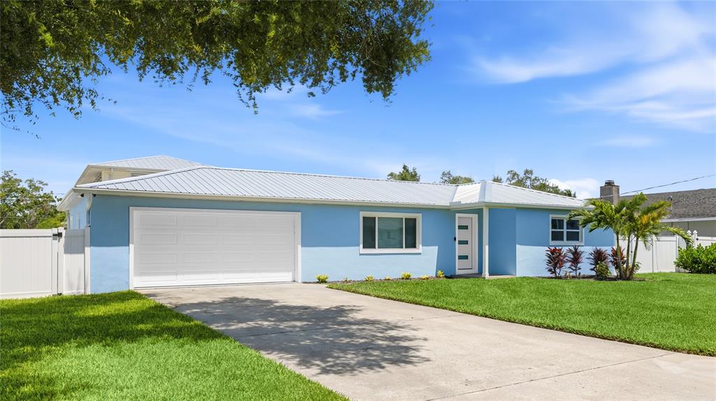 A light blue single-story house with a white garage door and a metal roof — 912 21ST AVENUE W, PALMETTO, FL
