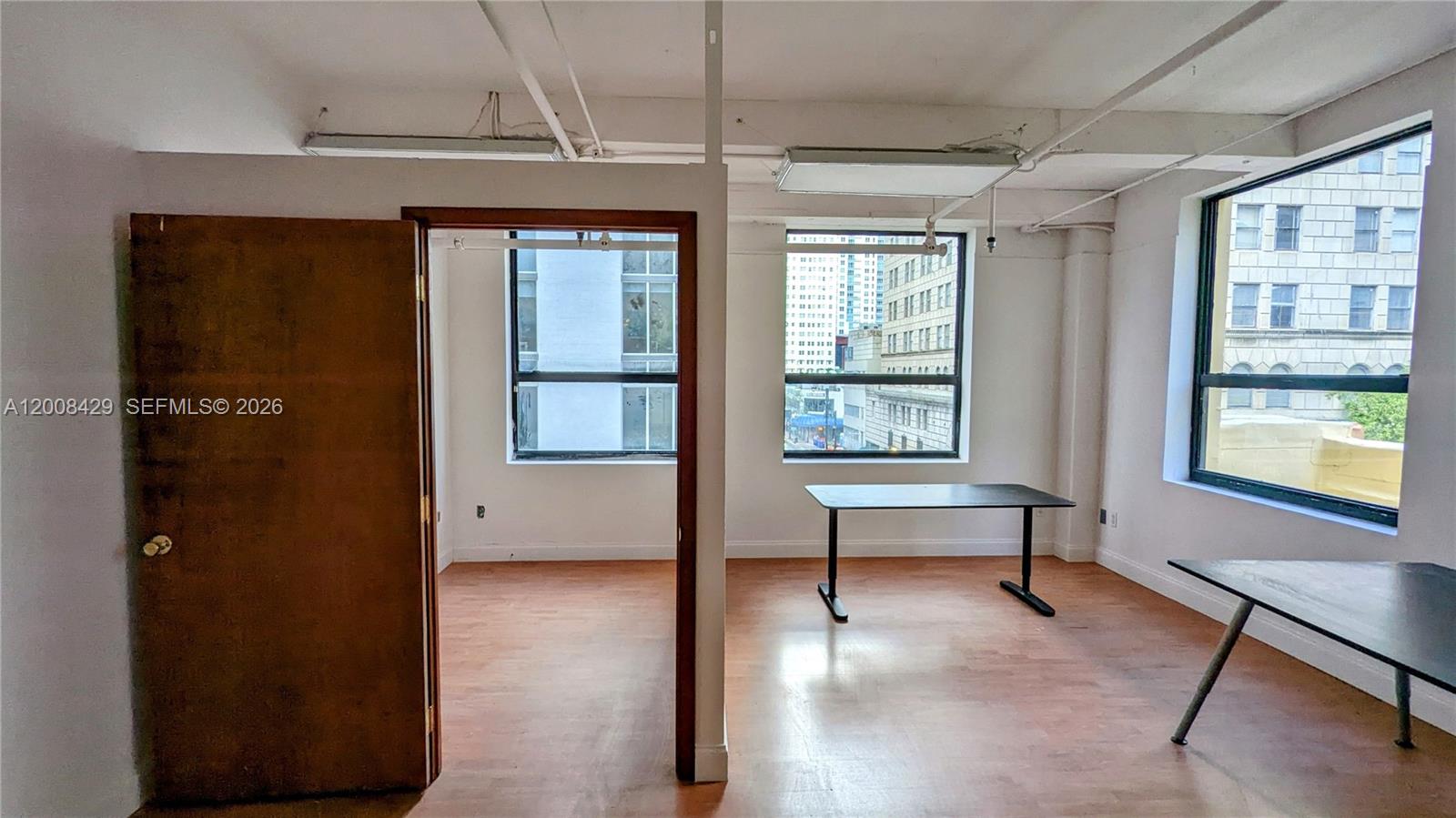 An office space features wood-look flooring, white walls, exposed ceiling beams, and large windows — 168 SE 1st St # 400, Miami FL 33131, MIAMI, FL