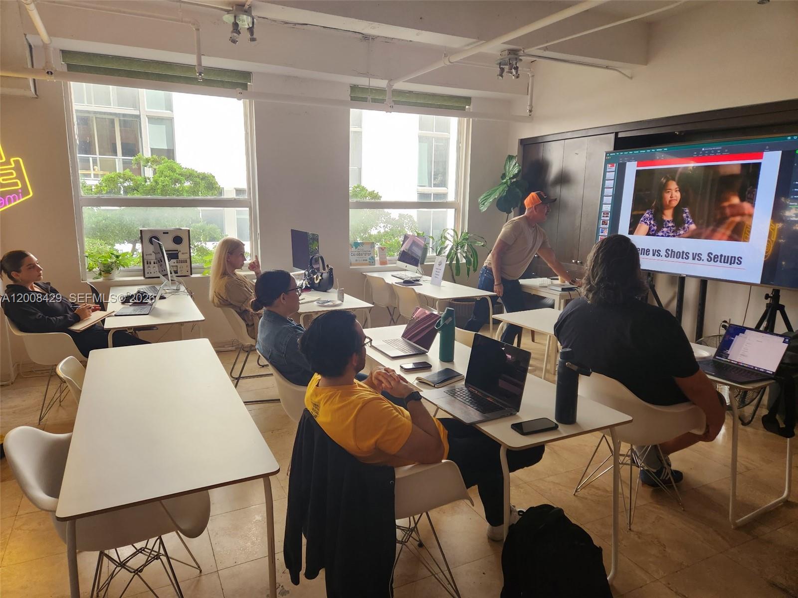 A classroom or office space features rows of desks, laptops, and a large presentation screen — 168 SE 1st St # 400, Miami FL 33131, MIAMI, FL
