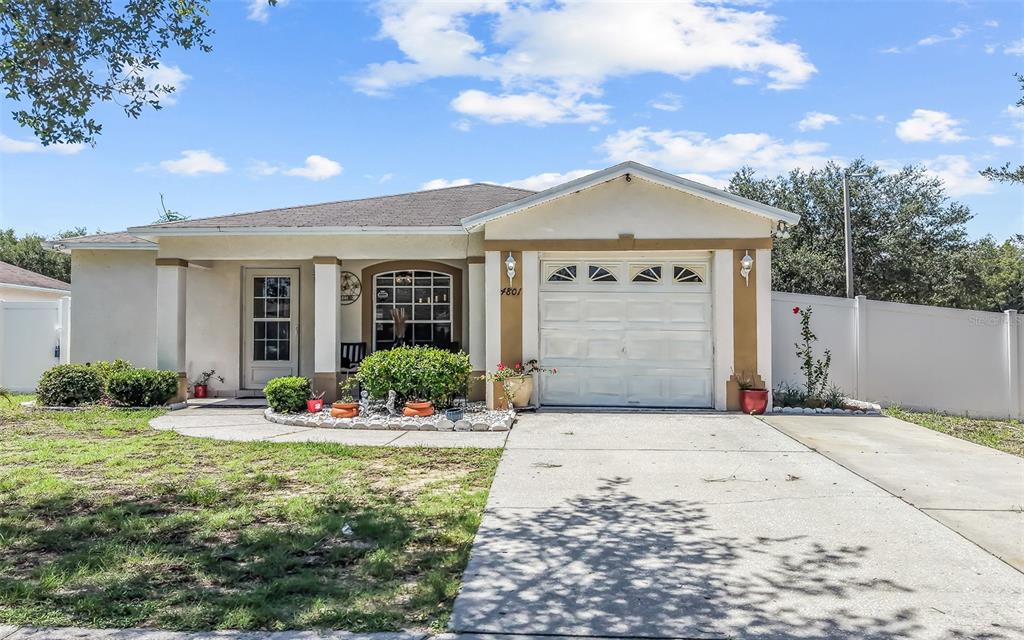 A single-story house features a white garage, a covered entryway, and a landscaped front yard — 4801 ROCK FISH COURT, TAMPA, FL