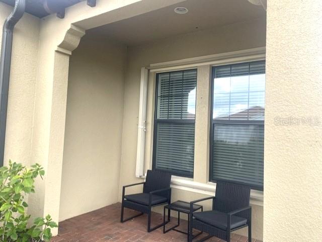 Two black chairs and a small table sit on a covered brick patio — 10485 CROOKED CREEK DRIVE, VENICE, FL