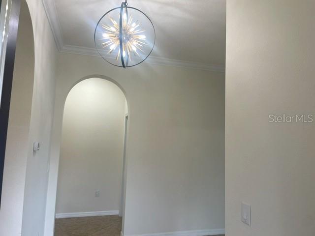 An interior view shows a hallway with an arched entryway and a modern sputnik chandelier — 10485 CROOKED CREEK DRIVE, VENICE, FL