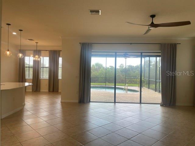 An open living area features tile floors, a ceiling fan, and sliding doors to a pool — 10485 CROOKED CREEK DRIVE, VENICE, FL