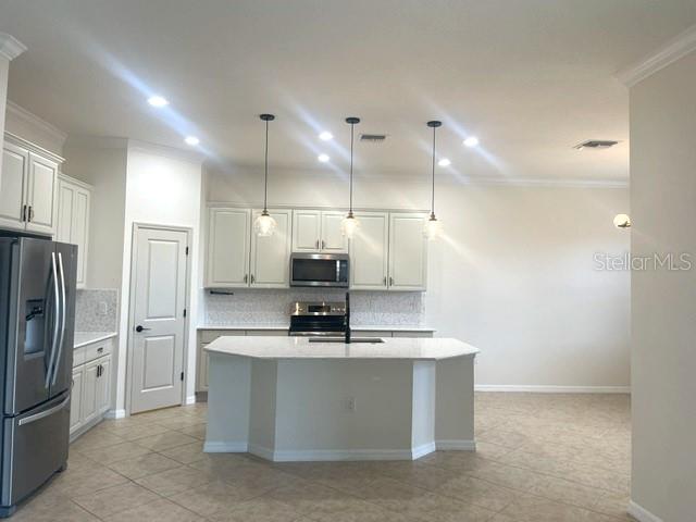 A kitchen features light-colored cabinetry, stainless steel appliances, a center island, and pendant lighting — 10485 CROOKED CREEK DRIVE, VENICE, FL
