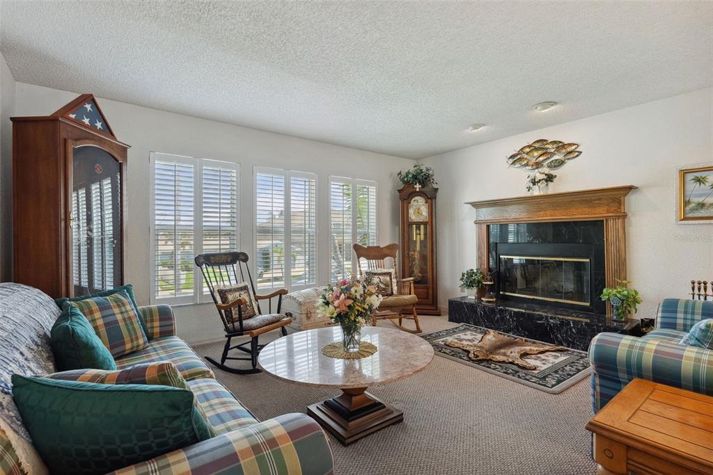 A living room features a plaid sofa, a fireplace with a marble hearth, and rocking chairs — 1842 BAYOU GRANDE BOULEVARD NE, ST PETERSBURG, FL