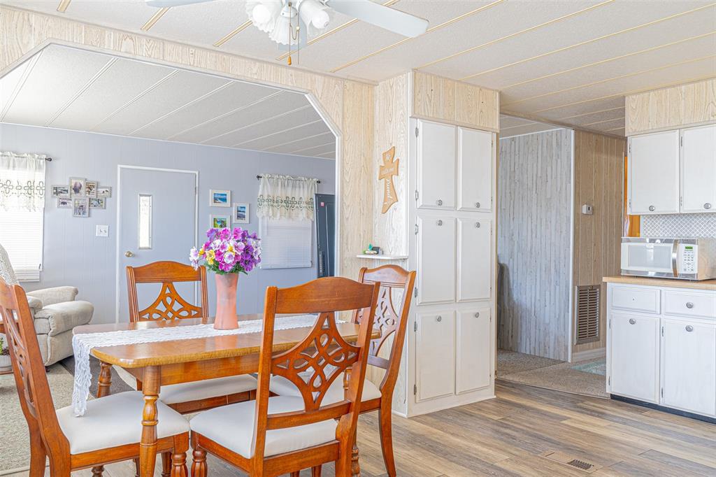 A dining area with a wooden table and chairs sits adjacent to a white kitchen — 4603 NEWCOMB AVENUE, ZEPHYRHILLS, FL