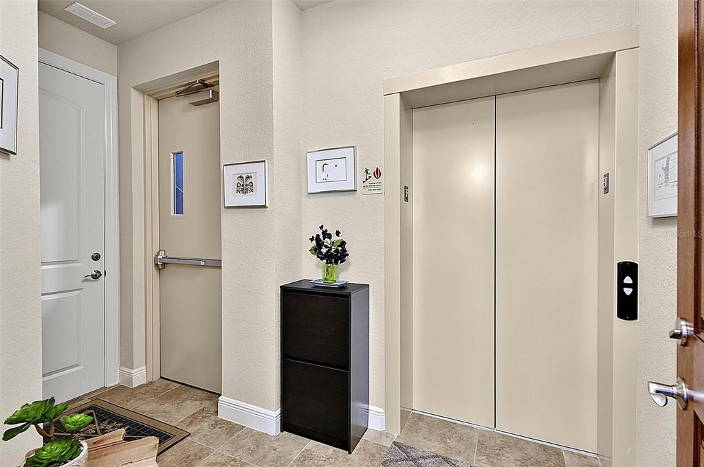 An interior hallway features a beige elevator, a metal door, and a black storage cabinet — 200 CEDAR COVE UNIT 205, PALM COAST, FL