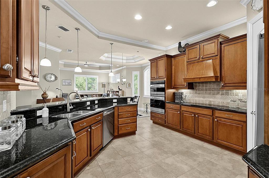 A kitchen with wood cabinets, black granite countertops, stainless steel appliances, and tile flooring — 200 CEDAR COVE UNIT 205, PALM COAST, FL