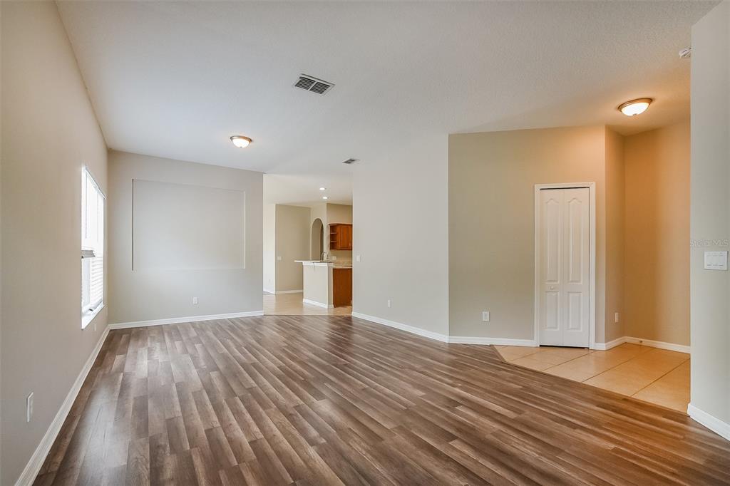 An open living room features wood-look flooring, a recessed wall niche, and a tiled entryway — 1221 LONGVILLE CIRCLE, TAVARES, FL