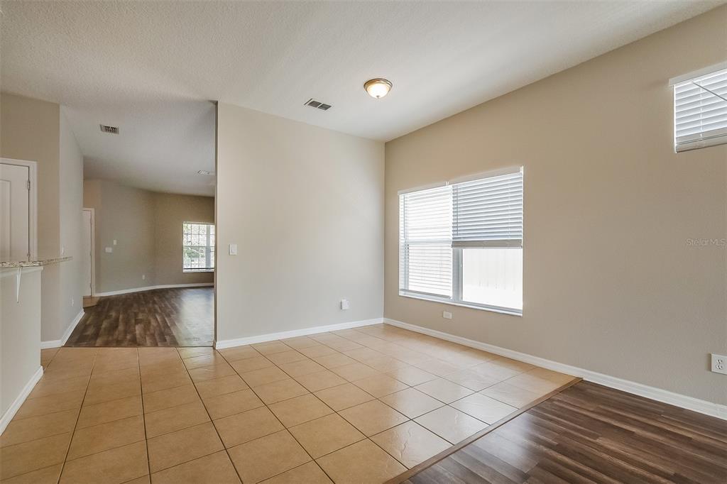 A dining area with beige tile flooring, neutral walls, and a large window with blinds — 1221 LONGVILLE CIRCLE, TAVARES, FL
