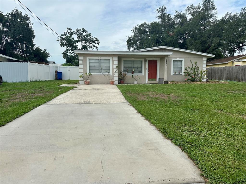 A single-story house with a concrete driveway, a red front door, and a grassy yard — 7507 CORAL VINE LANE, TAMPA, FL