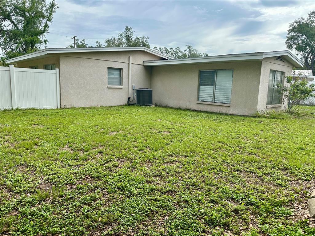 The exterior of a single-story house features a light-colored stucco finish and a grassy yard — 7507 CORAL VINE LANE, TAMPA, FL