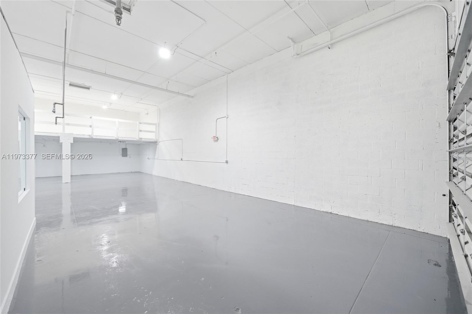 An empty industrial warehouse space features white block walls, a gray floor, and a mezzanine — 16300 SW 137th Ave # 119, Miami FL 33177, MIAMI, FL