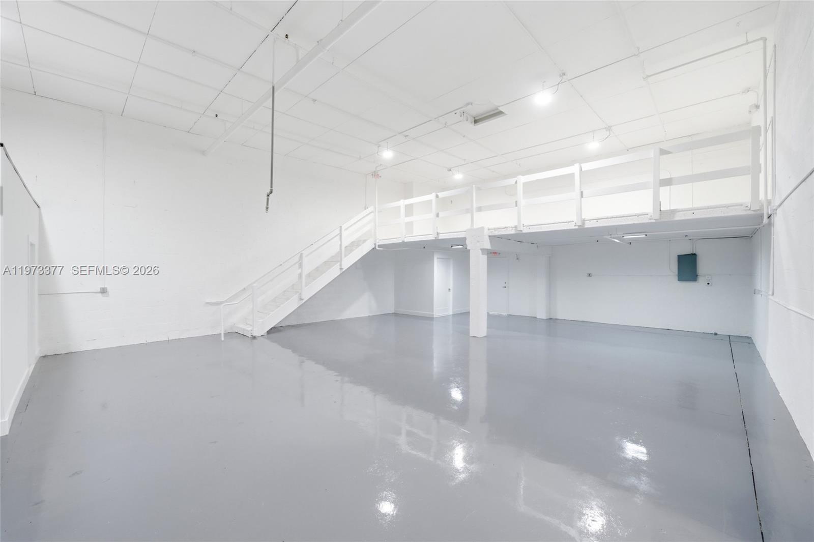 An industrial warehouse space features white walls, a gray floor, and a mezzanine with stairs — 16300 SW 137th Ave # 119, Miami FL 33177, MIAMI, FL