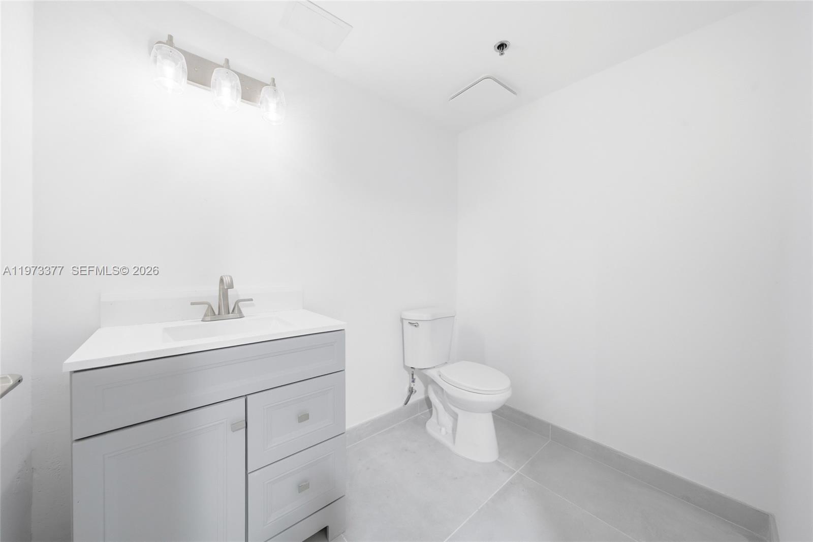 A modern bathroom features a gray vanity, white countertop, and a white toilet — 16300 SW 137th Ave # 119, Miami FL 33177, MIAMI, FL