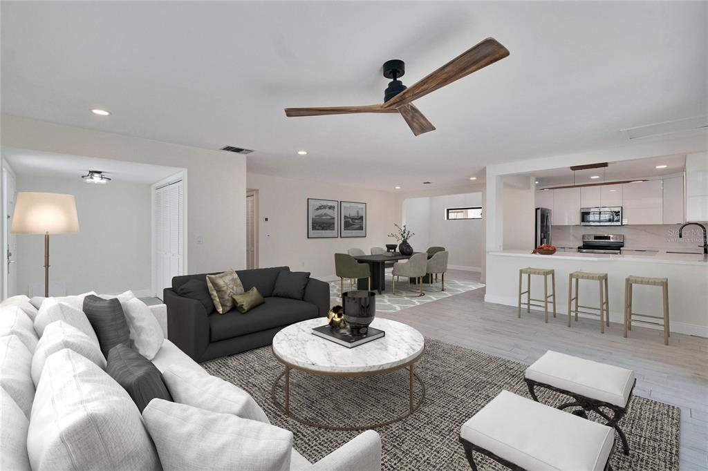 This is a digitally staged living room and kitchen with a ceiling fan and marble table — 370 S WOODLANDS DRIVE, OLDSMAR, FL