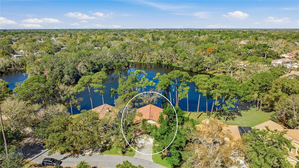 An aerial view shows a house with a tile roof surrounded by trees and water — 4870 TIVOLI COURT, SARASOTA, FL