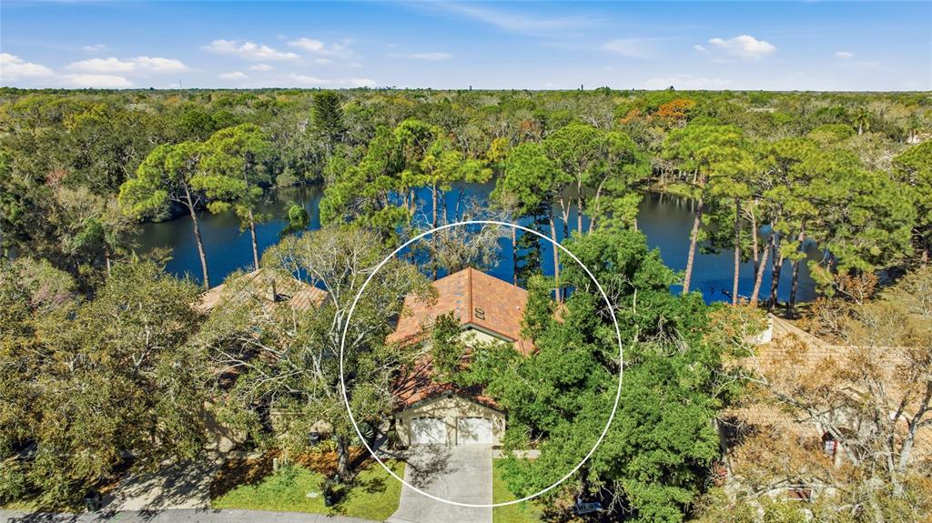 An aerial view shows a two-story house with a tile roof nestled among trees — 4870 TIVOLI COURT, SARASOTA, FL