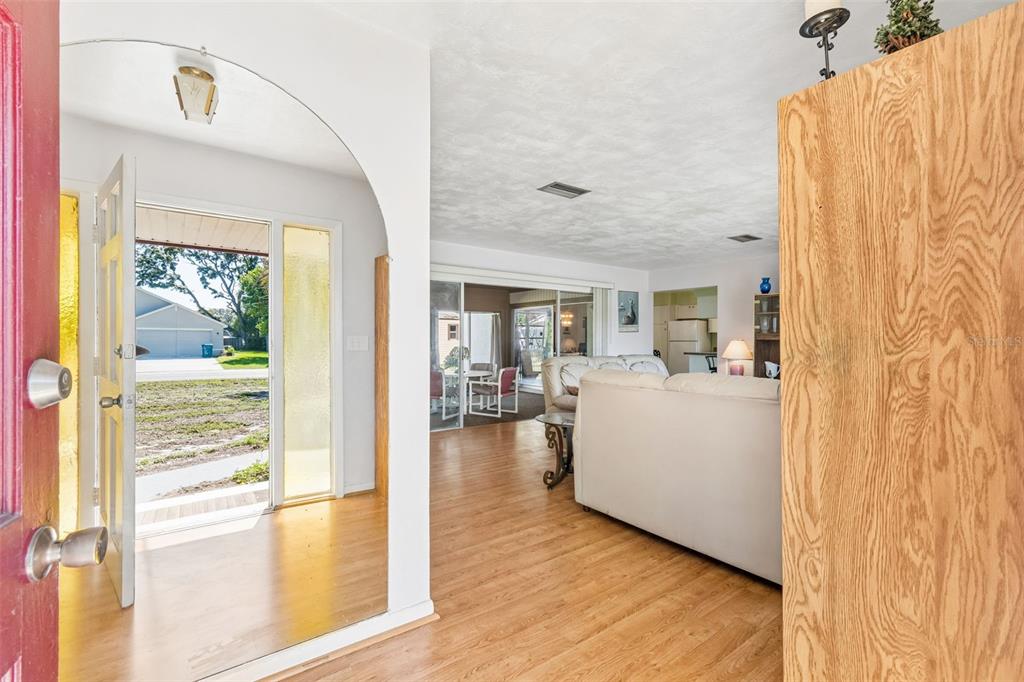A view from an entryway into a living room with wood flooring and an arched opening — 2059 WATERFALL DRIVE, SPRING HILL, FL