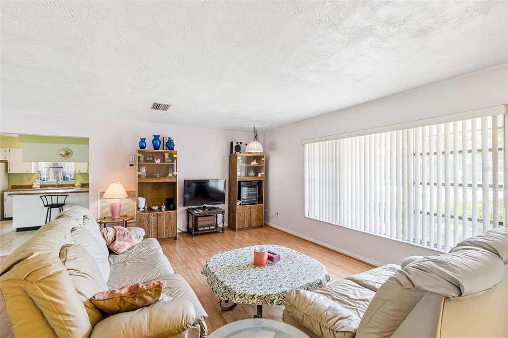 A living room with light-colored sofas, a round coffee table, and wood-look flooring — 2059 WATERFALL DRIVE, SPRING HILL, FL