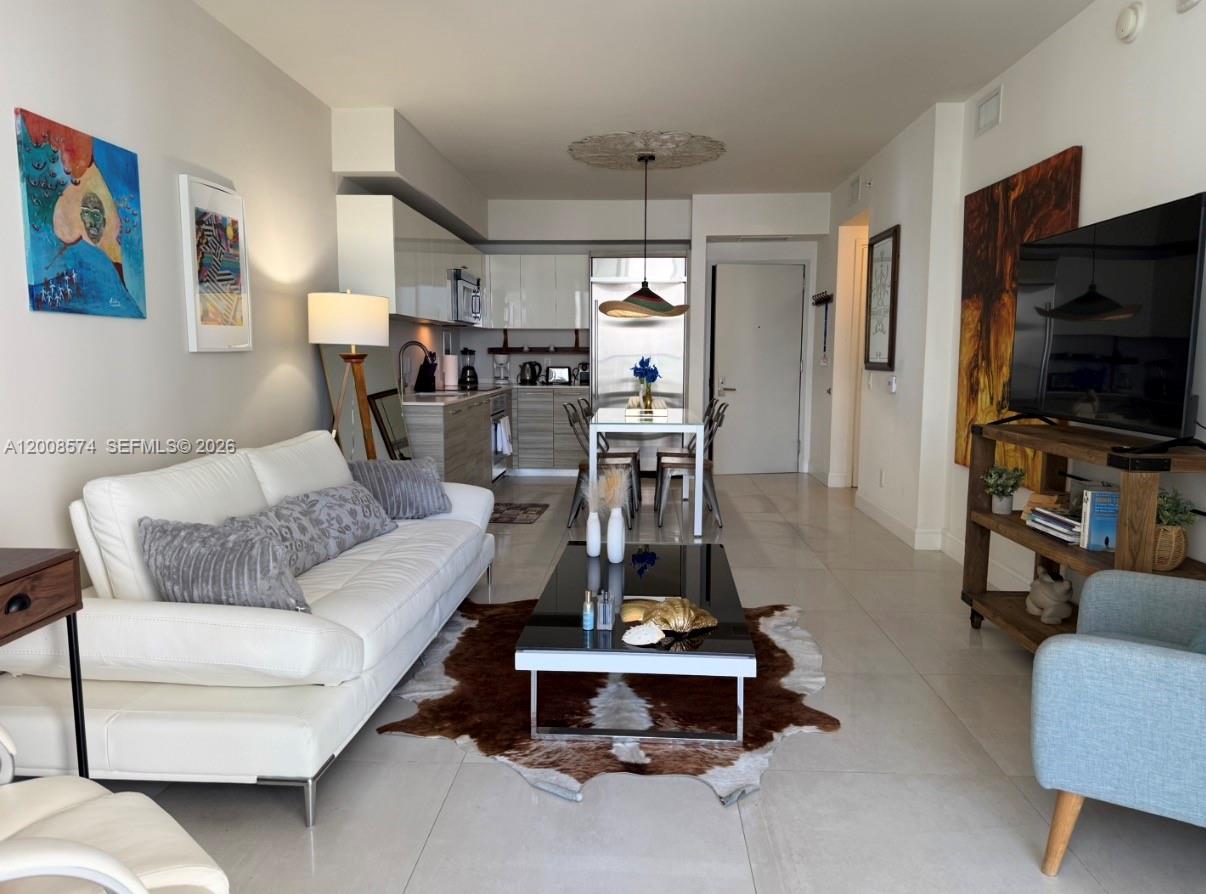A modern living room and kitchen area with white tile floors and a cowhide rug — 1300 Brickell Bay Dr # 807, Miami FL 33131, MIAMI, FL