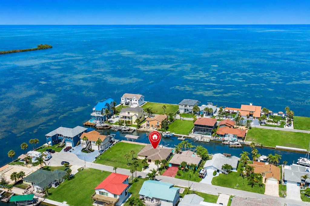 An aerial view shows a waterfront house with a red map pin in a coastal neighborhood — 13525 CLAUDIA DRIVE, HUDSON, FL