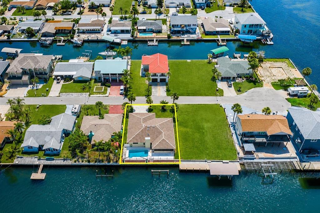 An aerial view shows a waterfront house with a pool and a large side yard — 13525 CLAUDIA DRIVE, HUDSON, FL