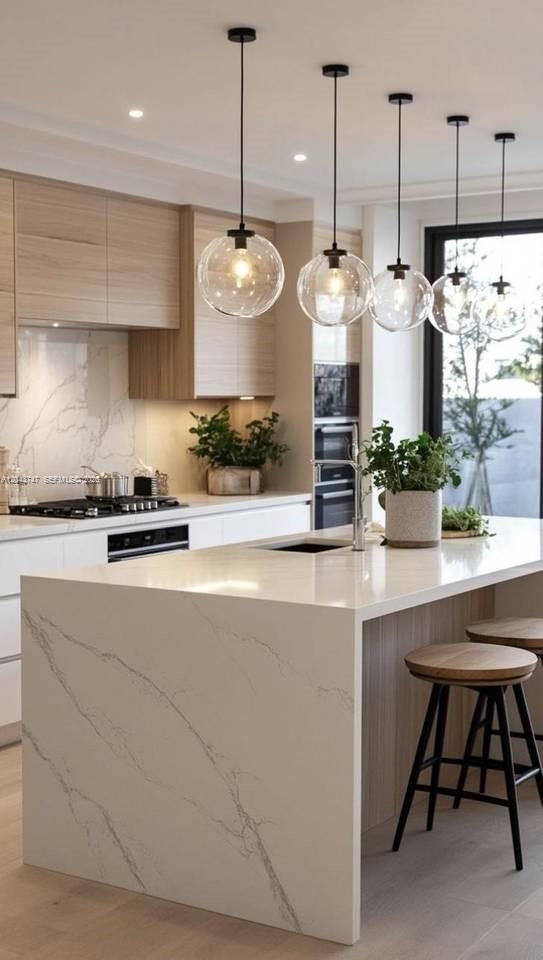 A modern kitchen features a marble waterfall island, light wood cabinetry, and five glass pendant lights — 0 villa camila, FL