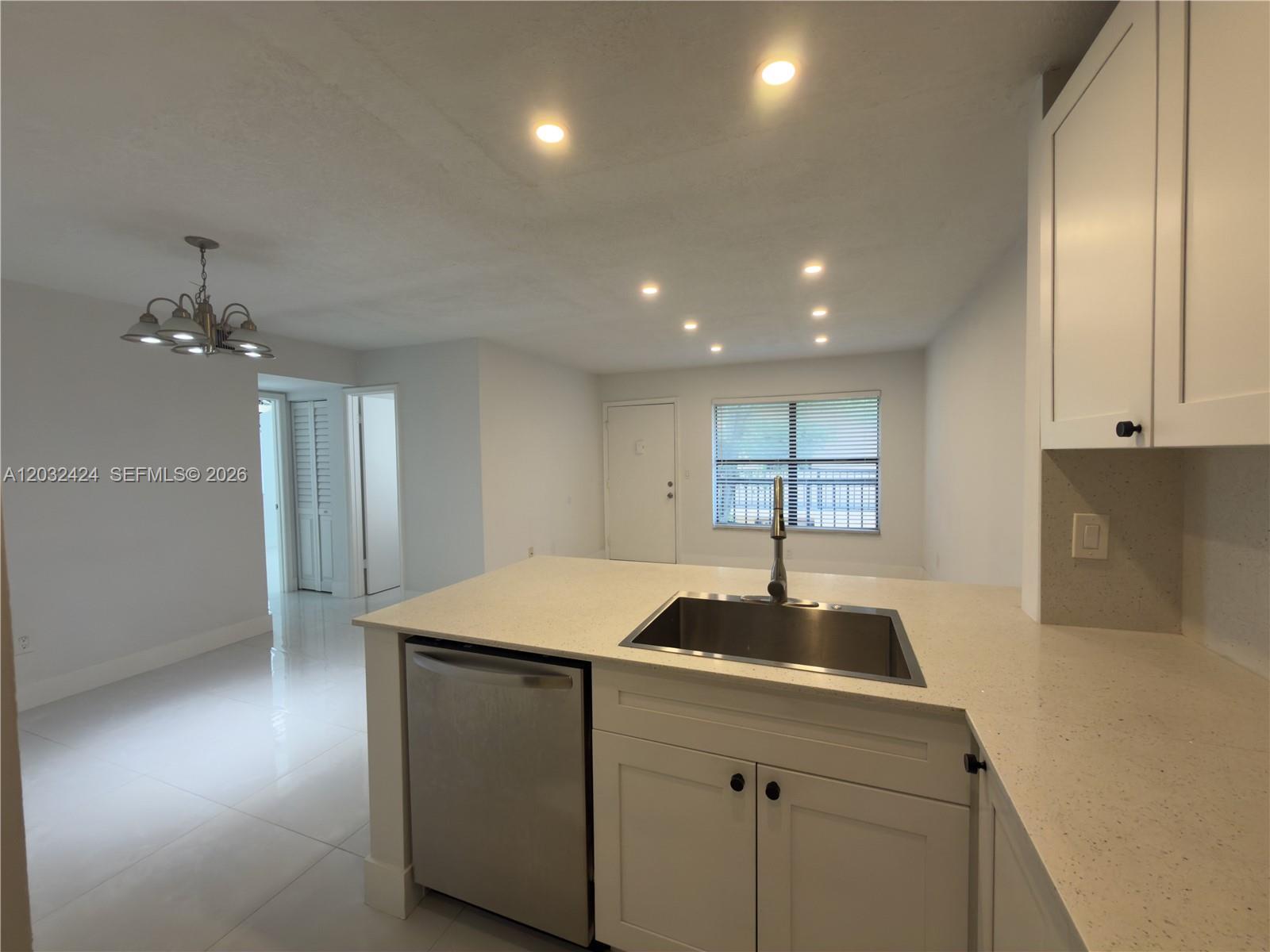 A kitchen features a stainless steel sink, white cabinets, and light-colored countertops — 2500 W 67th Pl # 26, Hialeah FL 33016, HIALEAH, FL