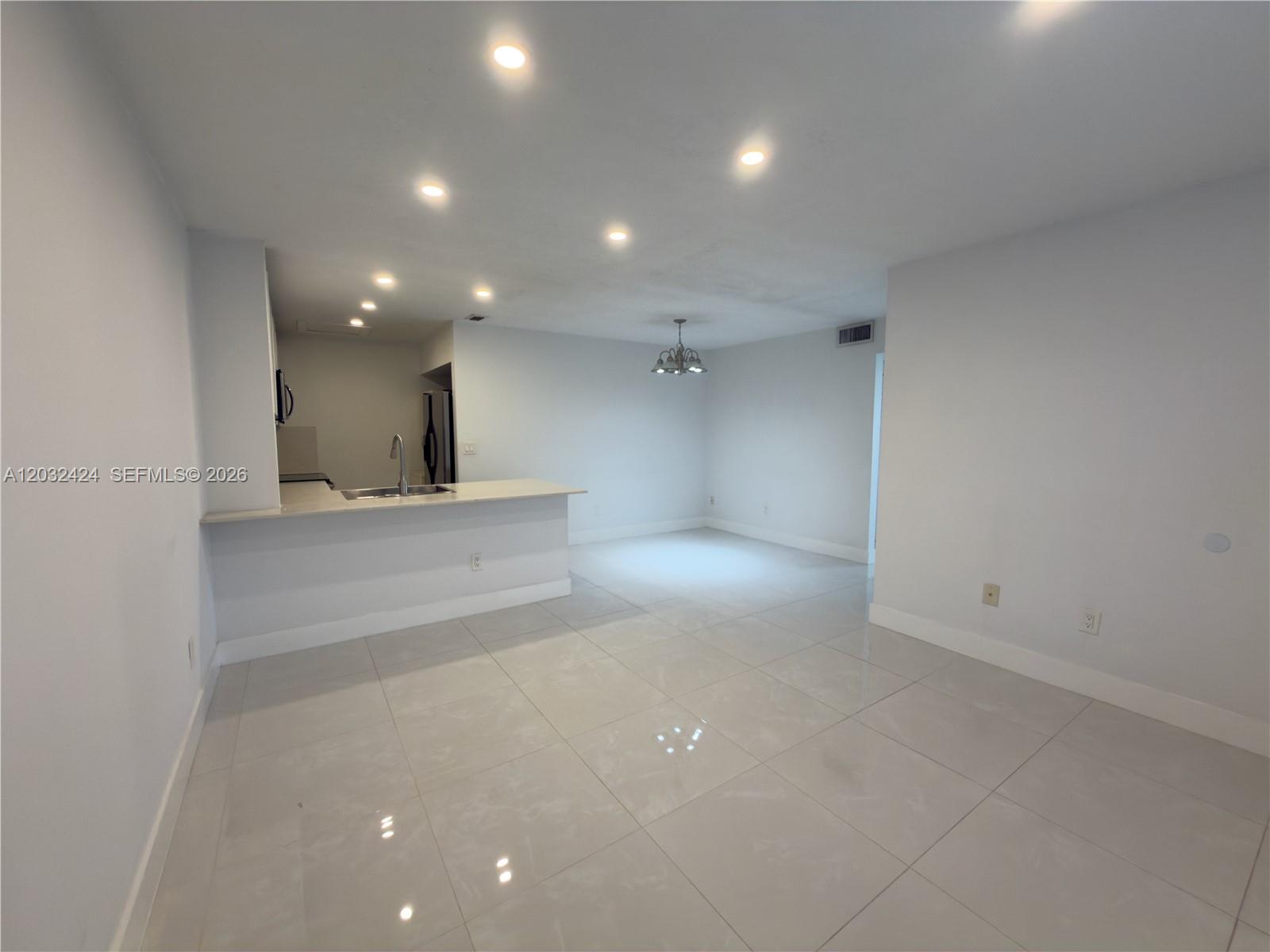 An open-concept living and dining area features white walls, light tile flooring, and a kitchen — 2500 W 67th Pl # 26, Hialeah FL 33016, HIALEAH, FL