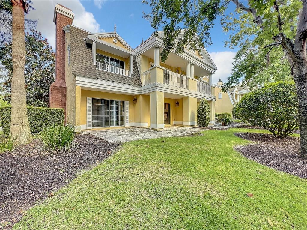 A two-story yellow house with a brick chimney, a patio, and a second-floor balcony — 7510 SEVEN EAGLES WAY UNIT 7510, REUNION, FL