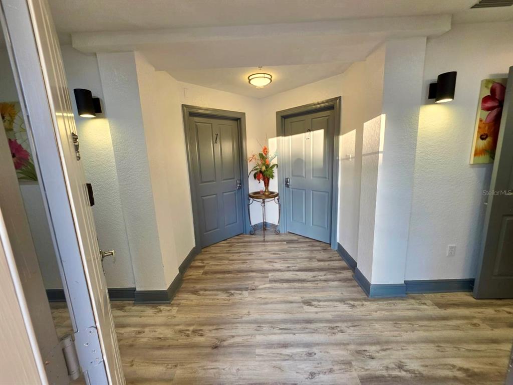 A hallway features wood-look flooring, two gray doors, and wall-mounted sconce lighting — 7510 SEVEN EAGLES WAY UNIT 7510, REUNION, FL