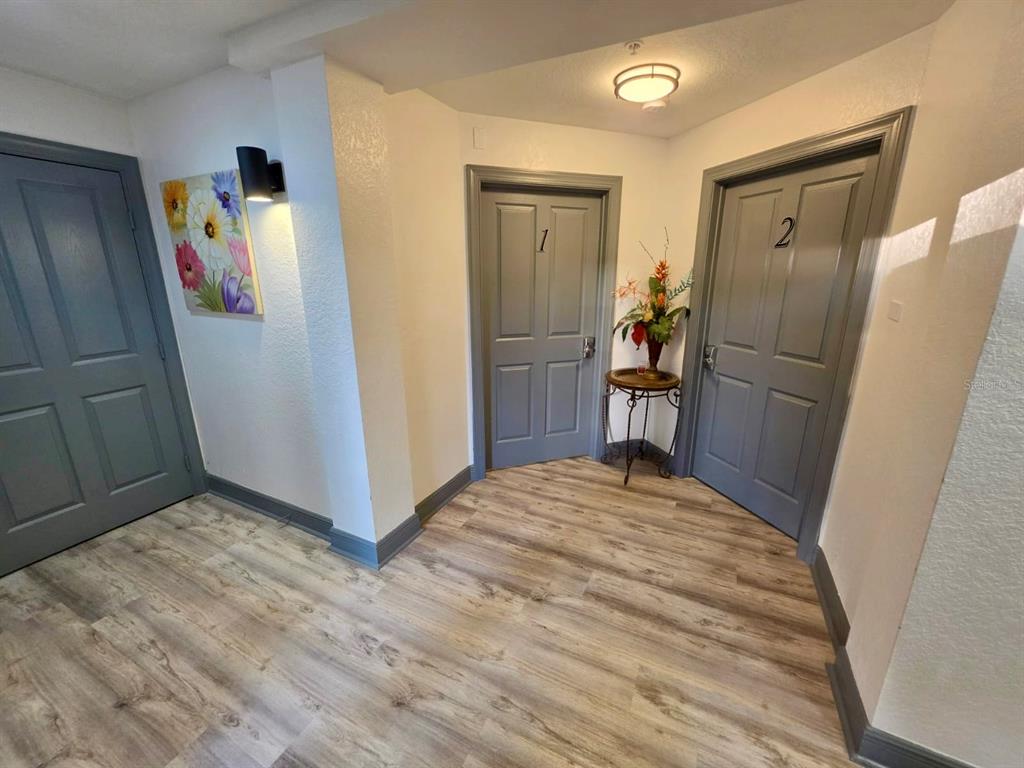 A hallway features light wood-look flooring, three gray doors, and a small decorative table — 7510 SEVEN EAGLES WAY UNIT 7510, REUNION, FL