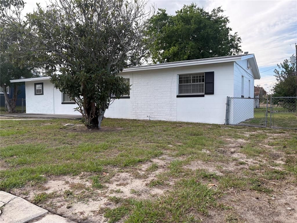A white, single-story house with a brick facade and a large tree in the yard — 2240 WHITE SANDS DRIVE, TITUSVILLE, FL