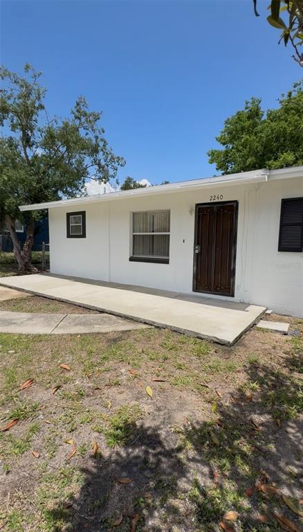 A white, single-story house with a concrete porch, a dark front door, and two windows — 2240 WHITE SANDS DRIVE, TITUSVILLE, FL